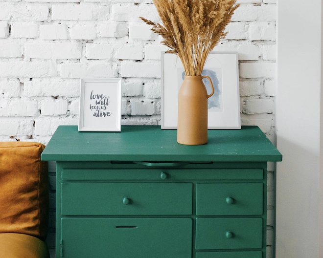 Green drawers with pictures on top and a flower pot.